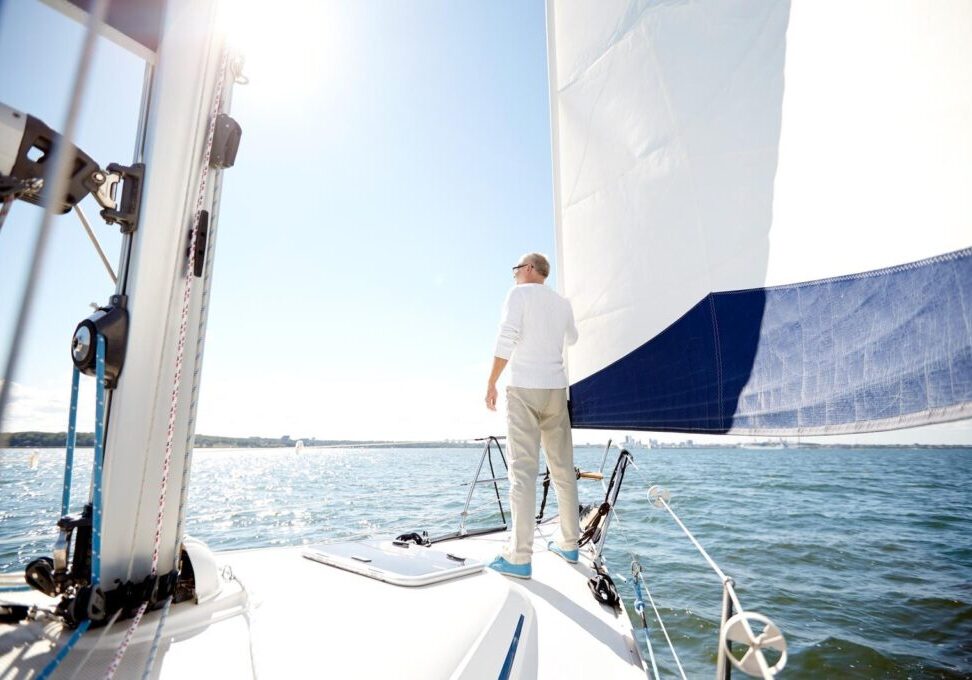 sailing, age, tourism, travel and people concept - senior man on sail boat or yacht floating in sea