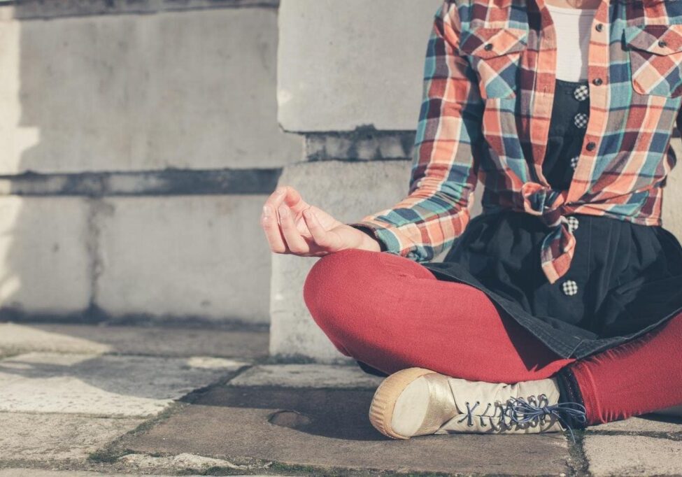 A young woman is sitting and meditating in the street